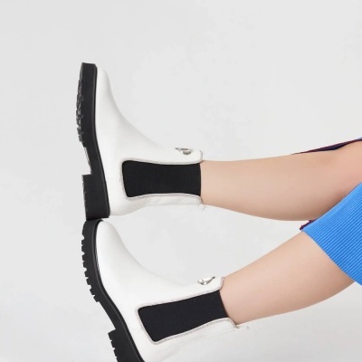 Botas brancas em pele com elásticos pretos e sola preta num fundo branco