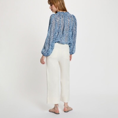 Blusa azul transparente com padrão floral e calças brancas