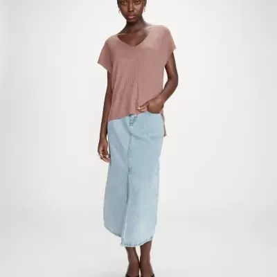 Mulher com camisola castanha de malha e saia comprida de ganga azul clara