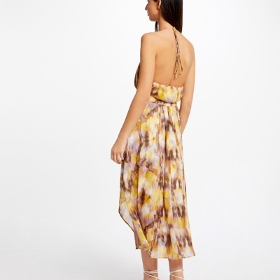 Mulher de costas a usar vestido midi estampado e sandálias de salto branco.