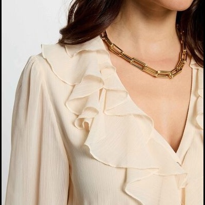 Blusa creme texturizada com folho no decote V e colar dourado de elos largos