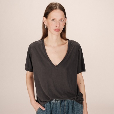 Mulher a usar t-shirt preta de manga curta e decote em V com calças de ganga azuis