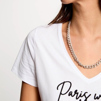 Pessoa com t-shirt branca com texto preto e colar prateado