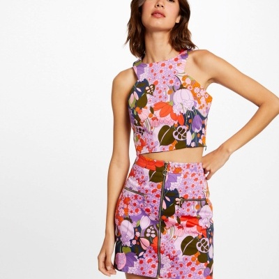 Conjunto feminino top cropped e saia curta com padrão floral colorido e fecho de correr frontal na saia.
