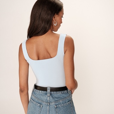 Mulher com top branco e calças de ganga vista de costas