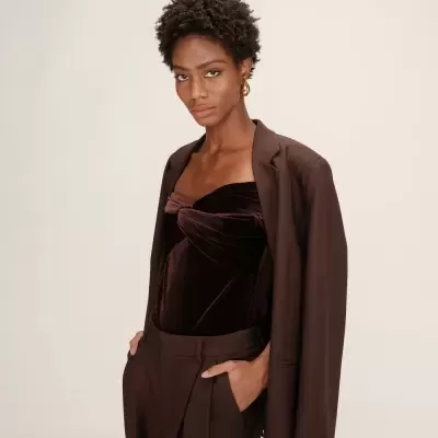Mulher veste blazer, top de veludo castanho e calças castanhas