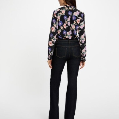 Mulher de costas a usar camisa preta floreada e calças de ganga pretas com costura amarela.