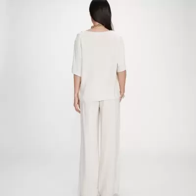 Conjunto feminino branco com blusa de mangas curtas e calças largas visto de costas.