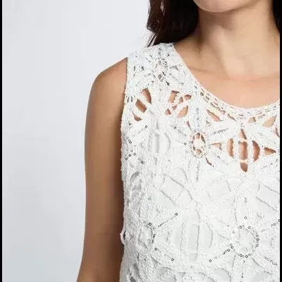 Blusa branca de crochet com padrões florais e detalhes brilhantes