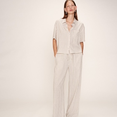 Conjunto feminino riscas bege e branco em modelo com fundo neutro