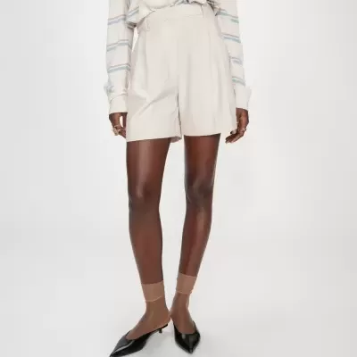 Calções bege de tecido com camisola de malha às riscas e sapatos pretos