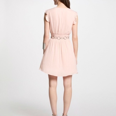 Vestido rosa claro curto visto de costas com cinto de argolas e sapatos prateados.