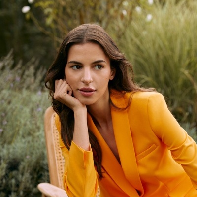 Mulher em fato amarelo sentada em cadeira de madeira ao ar livre