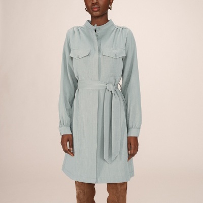 Vestido azul claro de manga comprida com cinto e bolsos frontais, usado com botas castanhas.