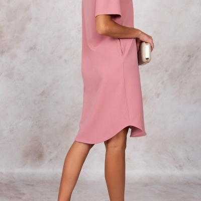 Mulher vestindo vestido cor-de-rosa com sandálias douradas e segurando carteira dourada