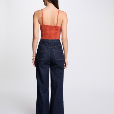 Modelo de costas vestindo top cropped vermelho texturizado e calças de ganga azul escuro largas