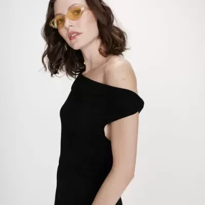 Mulher com vestido preto ombro a ombro e óculos amarelos transparentes