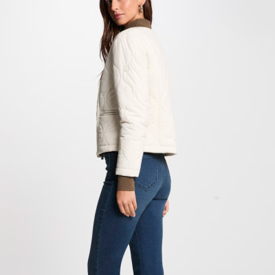 Casaco acolchoado branco de mulher com gola castanha e jeans azuis.