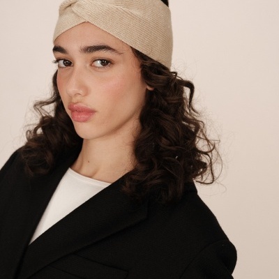 Mulher com faixa de cabeça bege de tecido e casaco preto