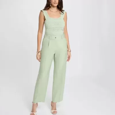 Mulher com top e calças verdes claras em fundo branco