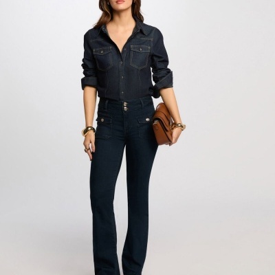 Mulher com camisa e calças de ganga azuis escuras, mala castanha e botins castanhos