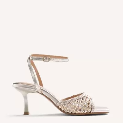 Sandália feminina de salto médio prateado com tira fina no tornozelo e parte da frente trançada.