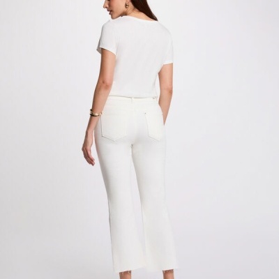 Modelo de costas com t-shirt branca e calças brancas de bainha desfiada, sandálias castanhas com tachas