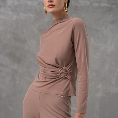 Conjunto feminino bege com blusa de manga comprida e calças, detalhe circular na cintura, fundo cinzento