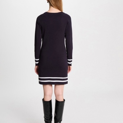 Vestido de malha preto com riscas brancas na parte de trás, usado com botas pretas.