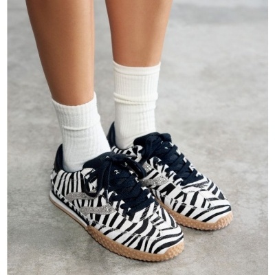 Sapatilhas com padrão de zebra preto e branco e atacadores pretos usadas com meias brancas