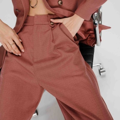 Conjunto de roupa rosa-aveludado com blazer e calças sentado numa cadeira preta de escritório