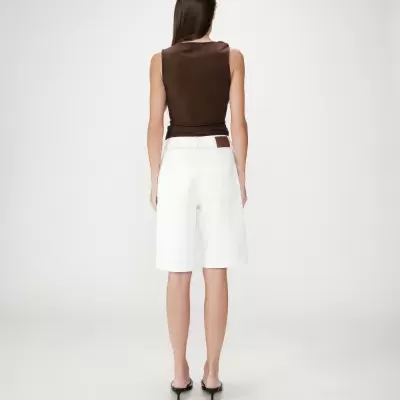 Mulher de costas com blusa castanha e calções brancos