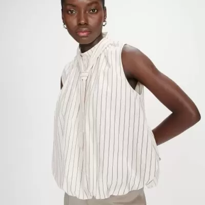 Blusa branca às riscas verticais pretas com nó ao pescoço, usada por mulher em fundo branco.