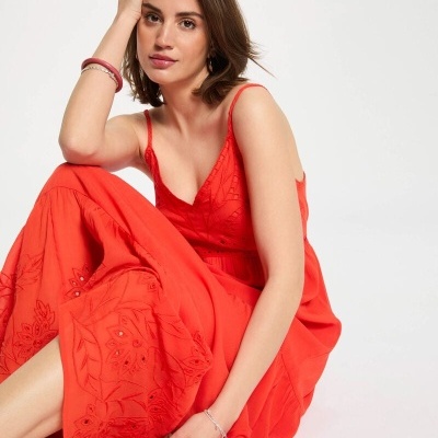 Mulher com vestido longo vermelho de alças finas e bordados florais