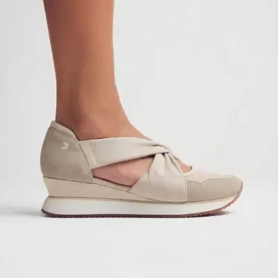 Ténis feminino bege com detalhe de nó e sola branca.