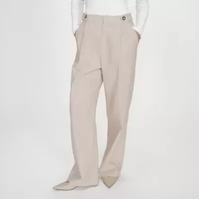 Calças largas bege com botões no cós, usadas com blusa branca e sapatos bege