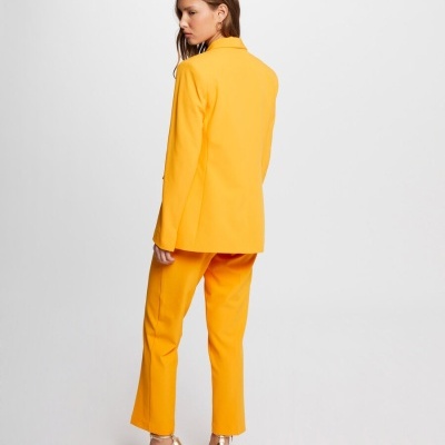 Mulher de costas vestindo conjunto amarelo com sapatos dourados