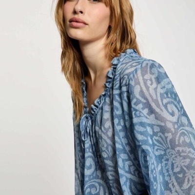 Blusa azul feminina com padrão floral e abstrato, gola frufru e laço no decote