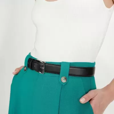 Top branco de malha canelada com calças verdes e cinto preto de couro.