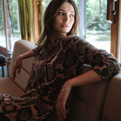 Mulher sentada no sofá com vestido de padrão de pele de cobra