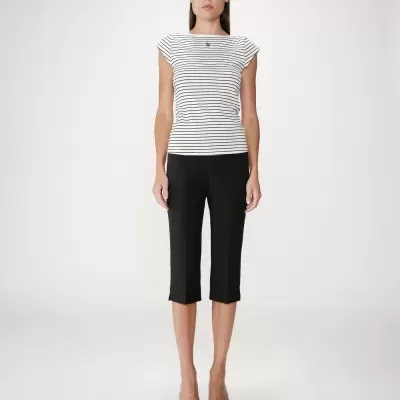 Mulher com blusa riscada preta e branca, calças pretas e salto alto preto