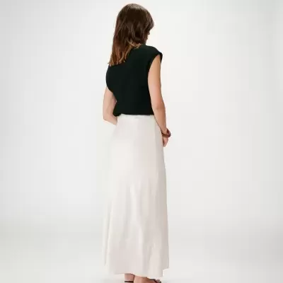 Mulher de costas com top preto, saia branca e sandálias pretas