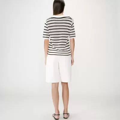 Camisola de malha branca às riscas pretas vista de costas com calções brancos.