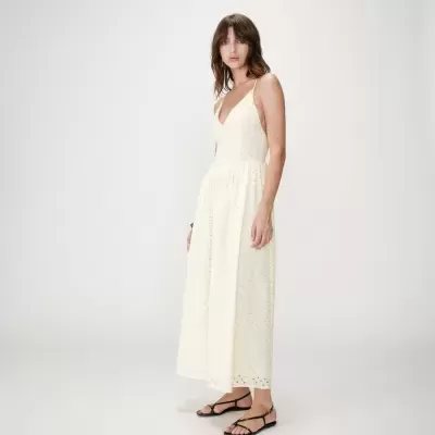 Vestido comprido branco com padrão de rendas e sandálias pretas em fundo branco