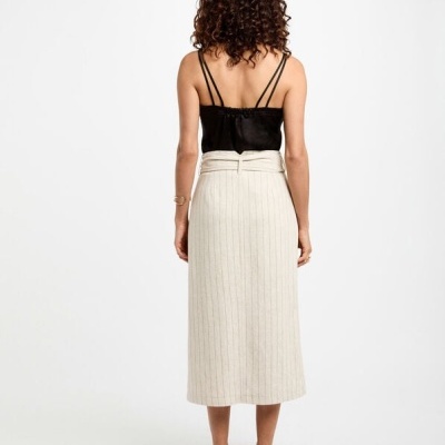 Vista traseira de mulher com saia comprida riscada bege e top preto alças finas