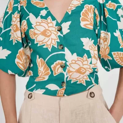 Blusa verde com padrão floral bege e branca e calças bege com botões na cintura