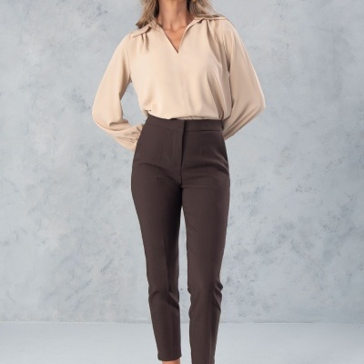 Mulher com blusa bege, calças castanhas e sapatos abertos