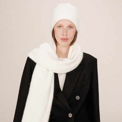 Mulher a usar gorro e cachecol brancos felpudos e casaco preto com botões cinzentos