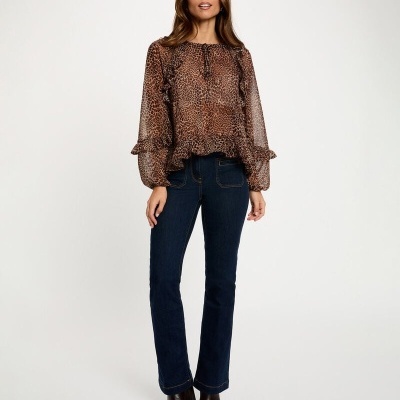 Mulher vestindo blusa animal print castanha transparente e jeans azul escuro com botas castanhas.