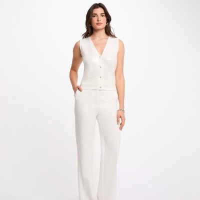 Mulher com colete branco de malha e calças brancas largas